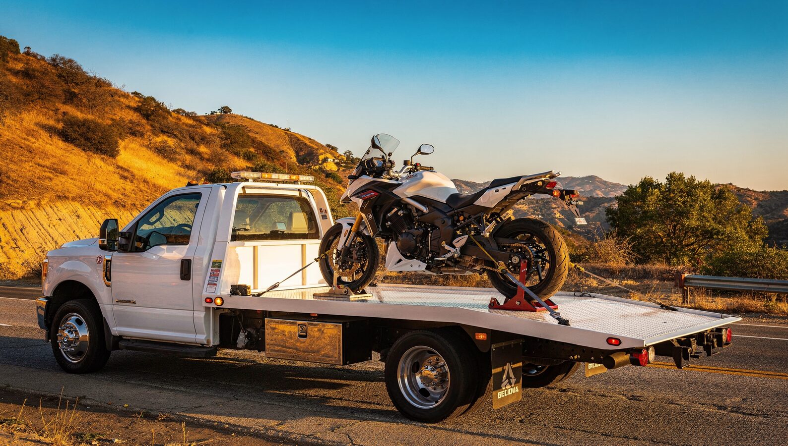 Motorcycle towing San Diego: bike chocked and strapped on a flatbed near a canyon road